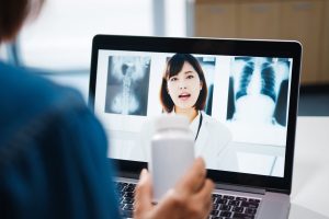 young-asia-lady-using-computer-laptop-talk-about-disease-video-conference-call-with-senior-doctor-online-consultation-living-room-home-1-scaled.jpg
